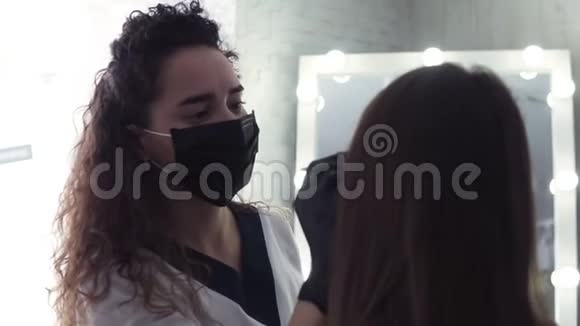 美容师戴着黑色面具用棉签擦着女人眉毛样式修正眉毛现代视频的预览图