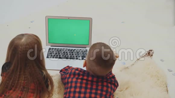 孩子们看着笔记本电脑屏幕与跟踪色度键绿色屏幕躺在白色地毯上的假期晚上视频的预览图