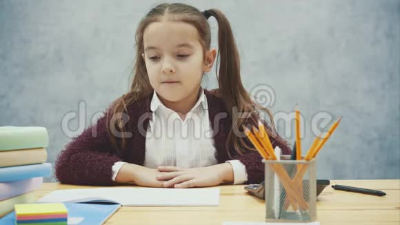 一个好的女学生坐在灰色背景的桌子旁在这段时间里他在五颜六色的叶子上画了一个微笑和微笑视频的预览图