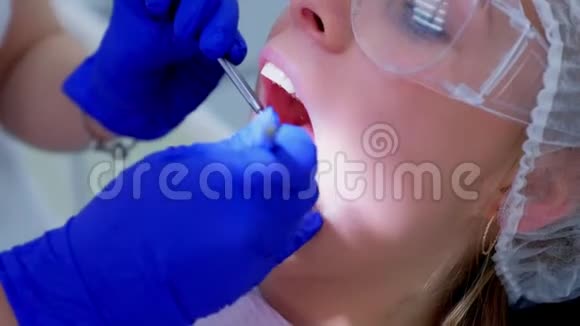 牙医检查女性患者牙齿使用牙科镜和钩子视频的预览图