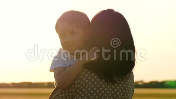 可爱的男孩拥抱他妈妈一个孩子的脸特写日落时幸福的家庭视频的预览图
