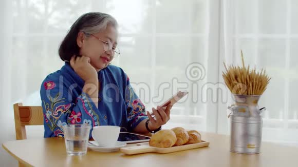 快乐的老年女性在放松时间阅读智能手机视频的预览图
