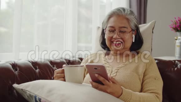 老年妇女听音乐用无线耳机说话视频的预览图
