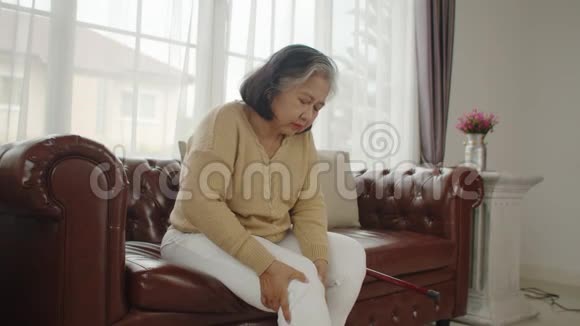 坐在沙发上按摩膝盖的老妇人视频的预览图