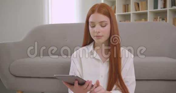 用平板电脑拍摄年轻漂亮红发女性的特写肖像并显示绿色彩色钥匙屏幕以拍摄坐姿视频的预览图