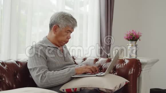 老人在笔记本电脑上打字开心地聊天视频的预览图