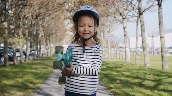 手里拿着滑板的微笑女孩正在公园里散步斯特迪卡姆视频的预览图