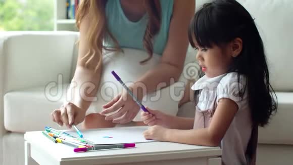 可爱的女孩选彩色铅笔和妈妈画画视频的预览图