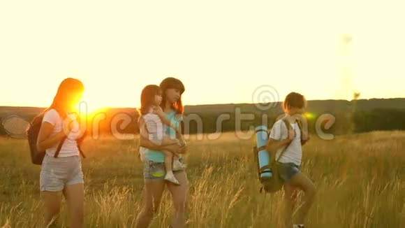 妈妈和她的女儿一起旅行母亲和孩子是游客女孩们在夕阳下穿越田野Hiker女孩视频的预览图