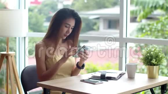 在咖啡店用智能手机的年轻美女视频的预览图