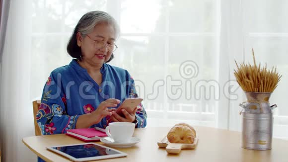 高级女性在咖啡店使用智能手机支付视频的预览图