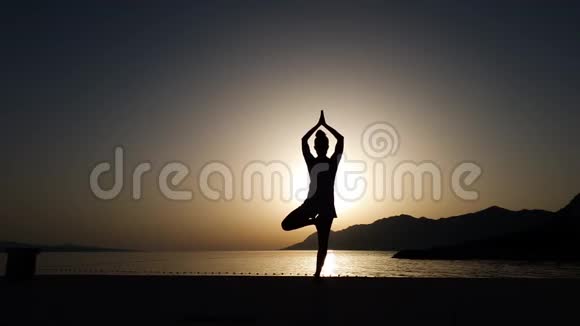海上日落时瑜伽体式女孩平衡剪影视频的预览图