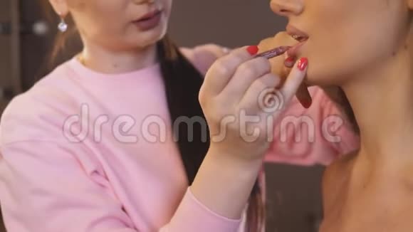 专业化妆师施粉面部化妆用毛笔坐在大镜子前的漂亮女孩视频的预览图