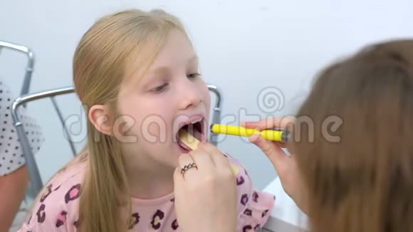 儿科医生看着孩子女孩喉咙痛使用铲子和灯笼视频的预览图