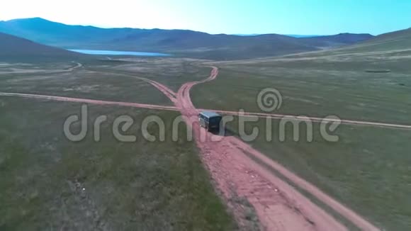 空中镜头拍摄与无人驾驶皮卡在草原汽车沿着草原行驶到西伯利亚铺设道路视频的预览图