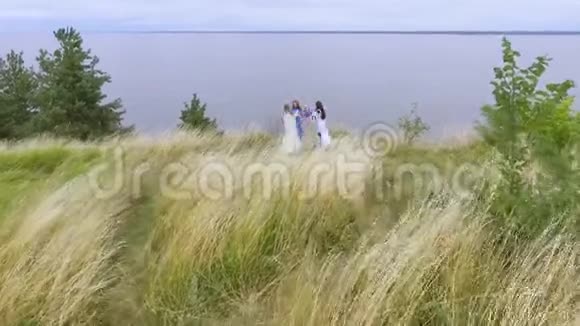 鸟瞰有趣的舞蹈女朋友穿着长长的夏季时尚连衣裙走在湖边或河边两个白人和视频的预览图