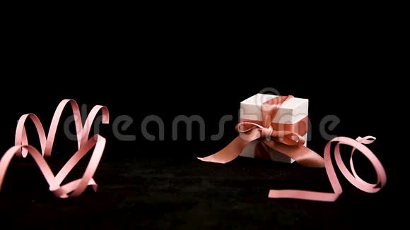 女式手黑色背景带粉色丝带的礼品盒视频的预览图