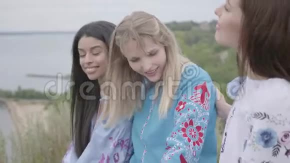 三个女朋友穿着漂亮的长裙刺绣坐在河岸边聊天概念视频的预览图