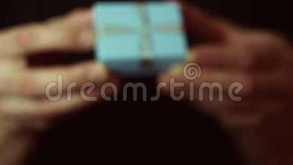 男人在一个蓝色的盒子里拿出一份礼物一个年轻人的手在一个蓝色小盒子里捧着新年礼物赠送礼品视频的预览图
