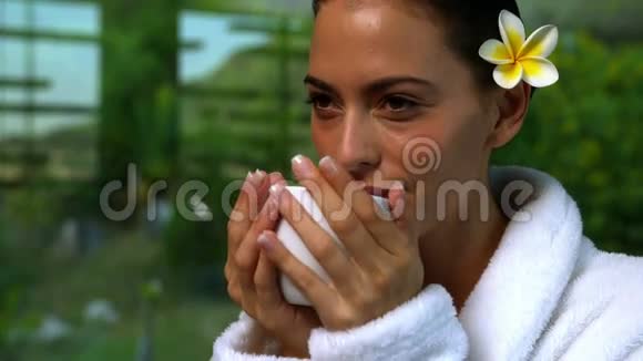 穿着浴袍的漂亮黑发女人在温泉里喝凉茶视频的预览图