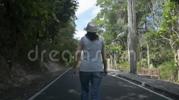 后景亚洲女人戴着草帽悠闲地走在路上视频的预览图