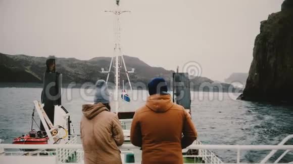 背面的男人和女人站在船上欣赏美丽的风景交谈探索冰岛的游客视频的预览图
