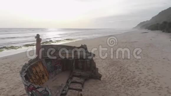 1Girl坐在沙滩上的一艘船残骸上视频的预览图
