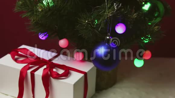 那人手把一件小礼物放在圣诞树下的一个蓝色盒子里视频的预览图