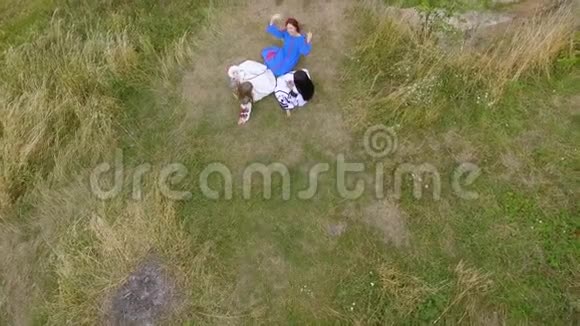 三个女朋友穿着长长的夏装躺在河边的一座高山上的鸟瞰图与自然的联系视频的预览图
