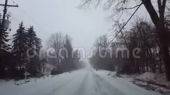 在白天驾驶冬季暴风雪在住宅郊区司机视角POV雪雪暴雪视频的预览图
