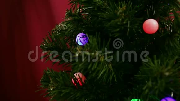 小女孩的手在圣诞树上挂着一个蓝色的球女孩装饰圣诞树视频的预览图
