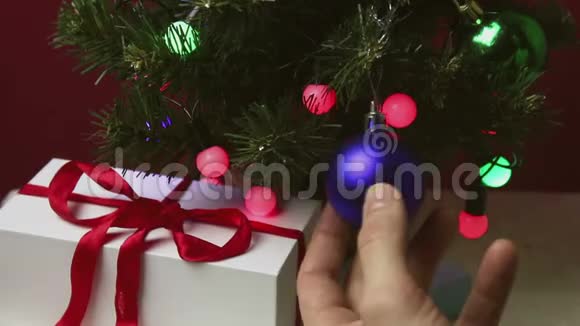 年轻人的手伸直了圣诞树上蓝色闪闪发光的球视频的预览图
