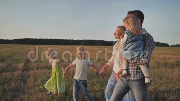 日落时一个大家庭沿着田野散步视频的预览图