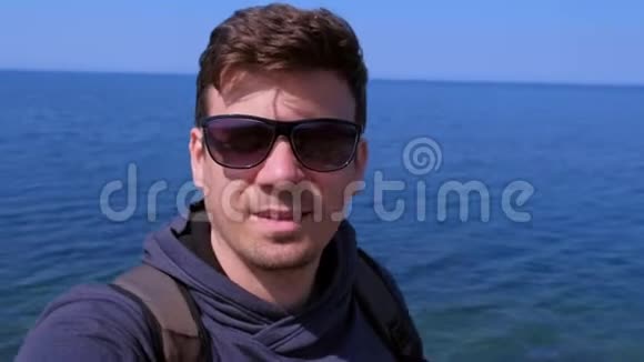 肖像男子视频聊天自拍智能手机在海上海滩和显示海上微笑视频的预览图