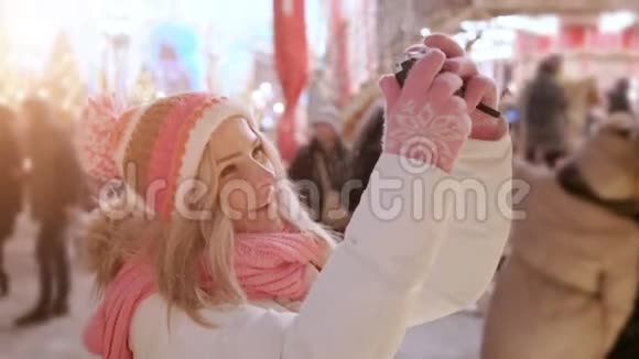 雪夜冬季市场上带复古照相机的年轻女子自拍视频的预览图