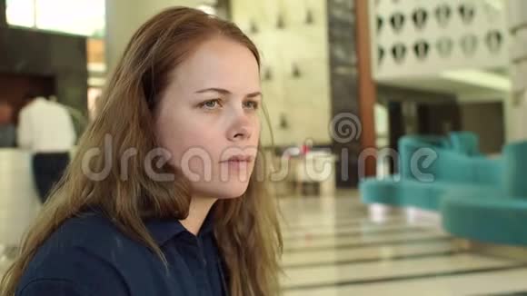 一个长发女孩在酒店大堂戴上太阳镜的特写镜头视频的预览图