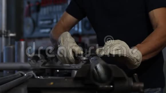 人在车库车间工作台上用锉刀夹着金属铁管自己动手双手合拢视频的预览图