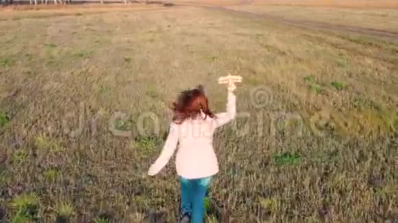 女孩跑过田野拿着飞机模拟飞行秋天晴朗的一天户外娱乐视频的预览图