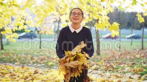女孩扔树叶在秋天公园玩得开心视频的预览图