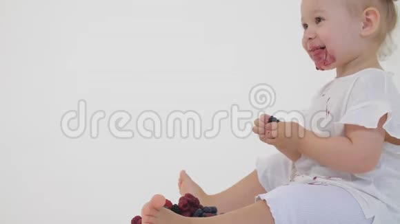 快乐的宝贝女孩吃多汁的浆果淡背景视频的预览图