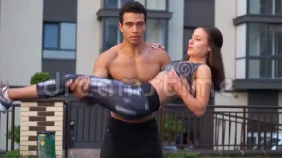 男人把女孩抱在怀里自我减肥运动美丽的健身模特惊人的表演训练夫妇视频的预览图
