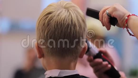 理发师用剪刀在男孩的头上剪头发视频的预览图