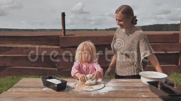 一个小女孩揉面团她的母亲支持她自制面包烘焙视频的预览图