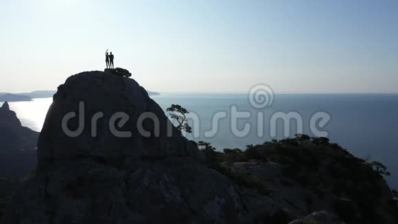 日出时一对年轻的恋人站在山顶上挥舞着双手视频的预览图