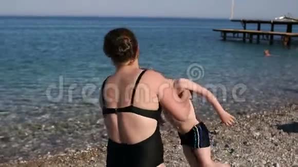 妈妈带着一个小孩子在海边的沙滩上旋转慢动作视频的预览图