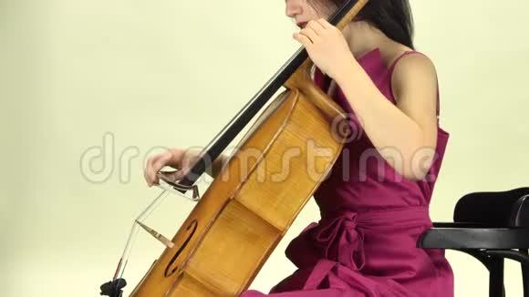 女人坐着玩大提琴侧视白色背景视频的预览图