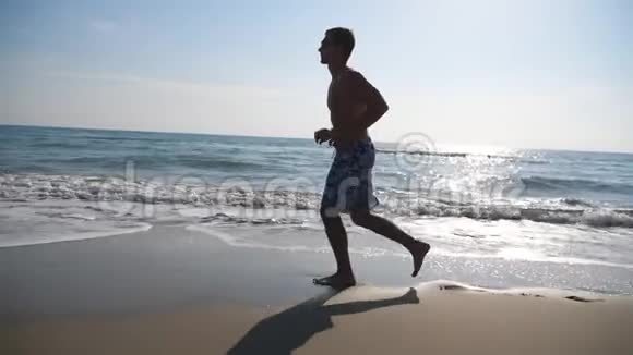 运动帅哥在美丽的海景背景下慢跑年轻的运动员沿着海边奔跑男性视频的预览图