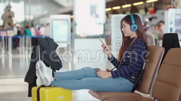 年轻女性旅客从机场的耳机听音乐视频的预览图