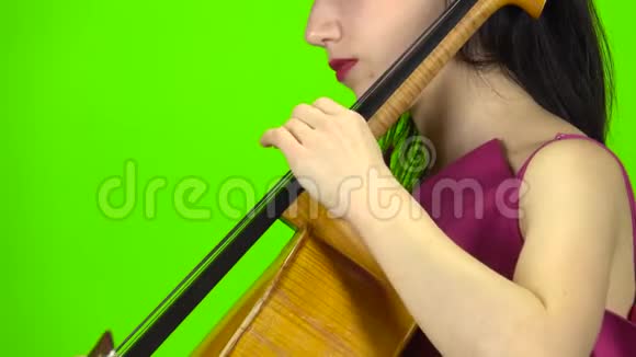 女孩用手指钉大提琴绿色屏幕侧视关门视频的预览图
