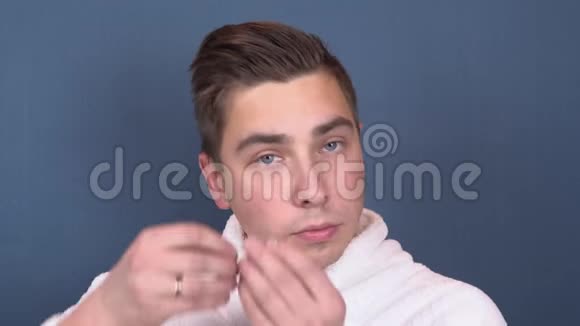一个年轻人把补丁贴在脸上蓝色水凝胶贴片以恢复面部皮肤的活力坐在里面的人视频的预览图